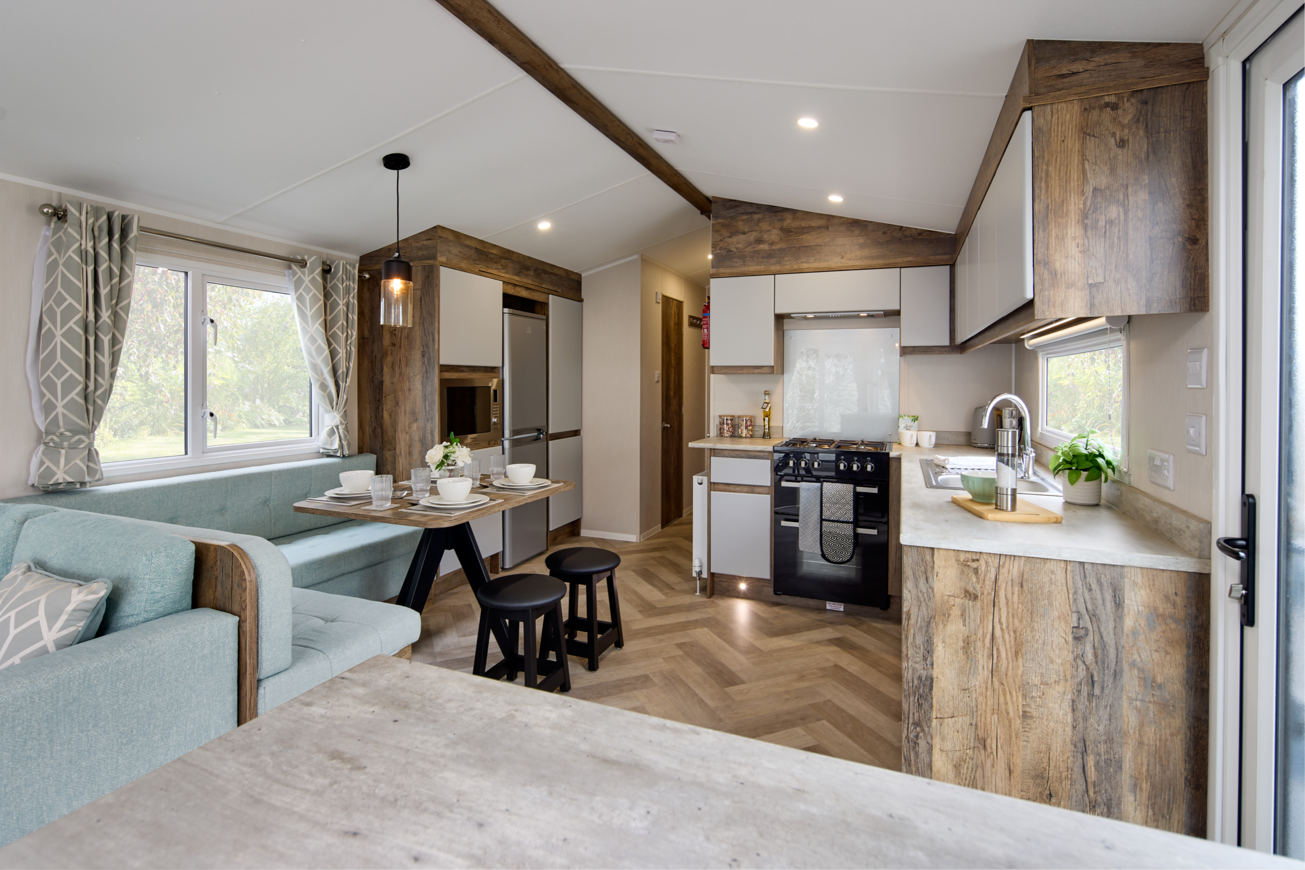 A bright, modern open-plan kitchen and dining area in the Willerby Brookwood holiday home, featuring white cabinetry and integrated appliances.